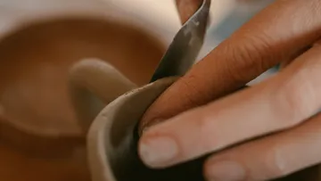 Hand formt Keramik mit Werkzeug, Nahaufnahme.