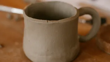 Tonbecher auf Holzoberfläche, unfertig.