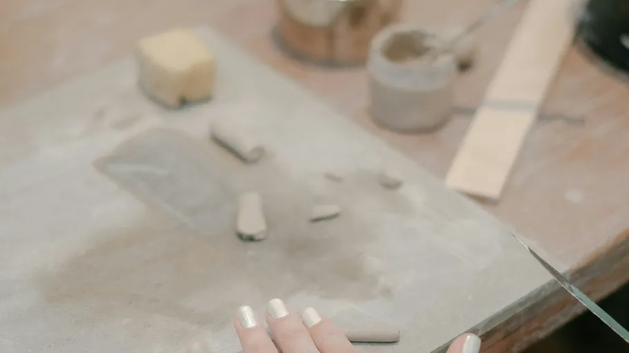 Hands shaping clay on a messy table.