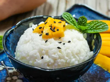 Schale mit Reis, Mango und Minze, appetitlich angerichtet.