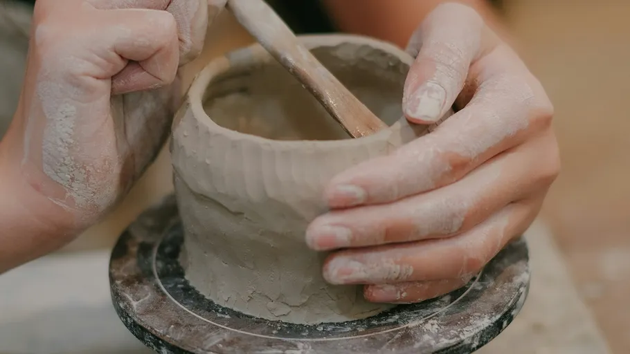Hands shaping clay on a pottery wheel.