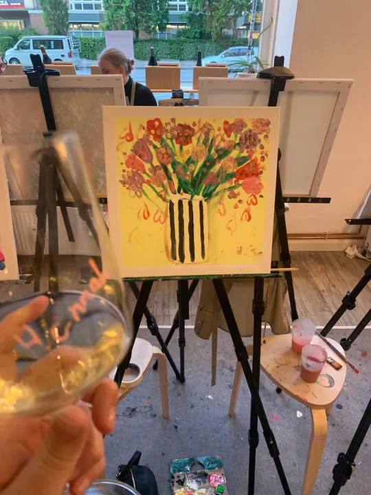 Malkurs mit Weinglas und Blumenbild.