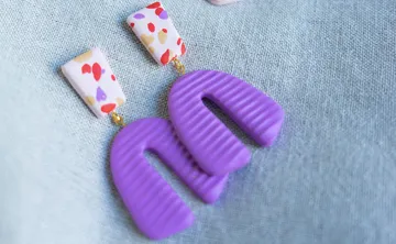 Bunte Ohrringe auf hellem Stoffhintergrund.
