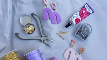 Craft supplies and pliers on a gray background.