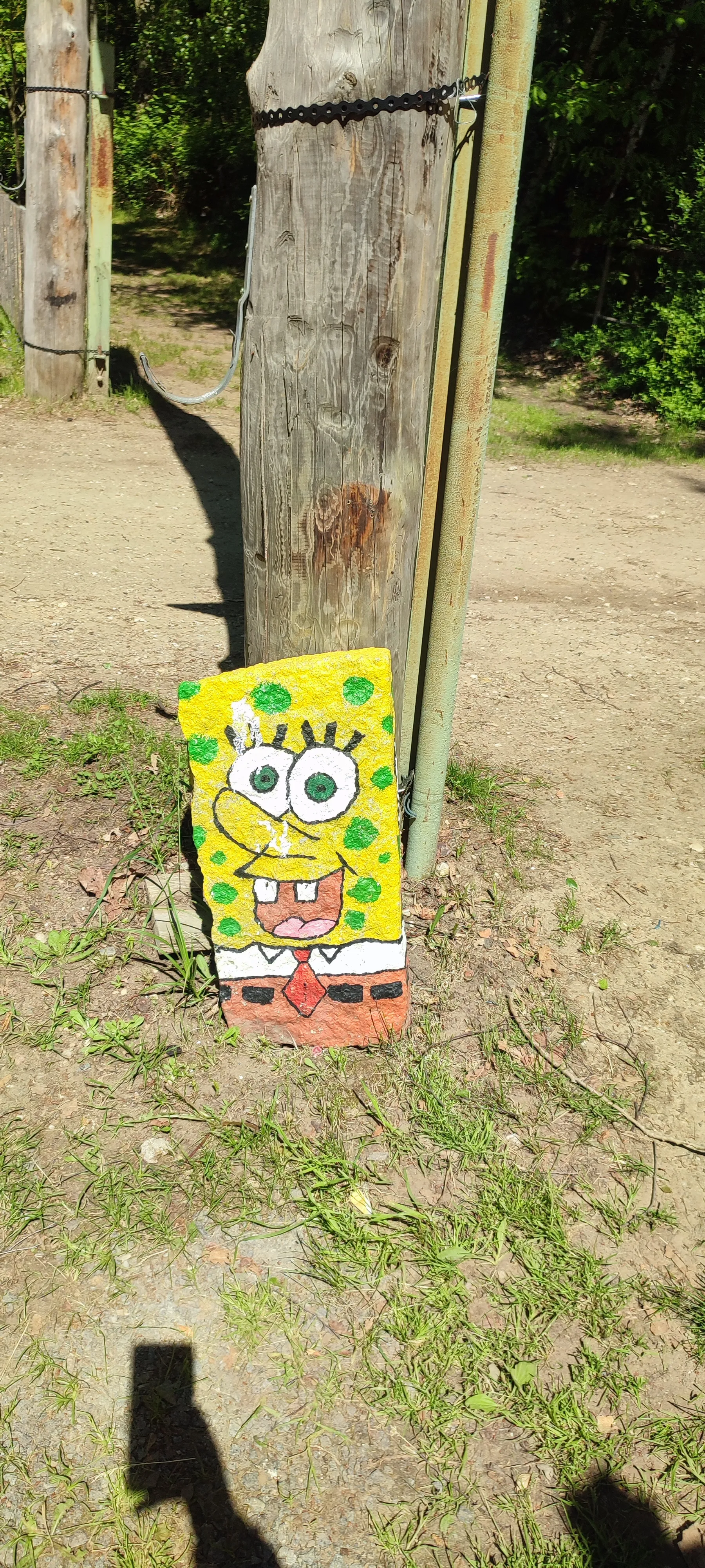 SpongeBob-Gemälde auf Stein neben Holzpfosten.