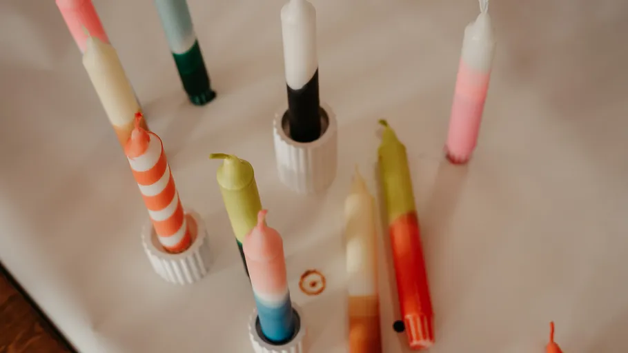 Colorful candles standing on a white surface.