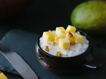 Schüssel mit Reis, gewürfeltem Obst, umgeben von Früchten.