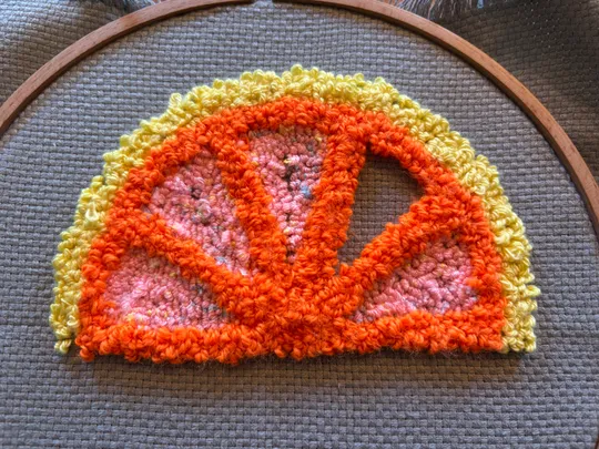 Bunte Häkel-Zitrusscheibe in Stickrahmen.
