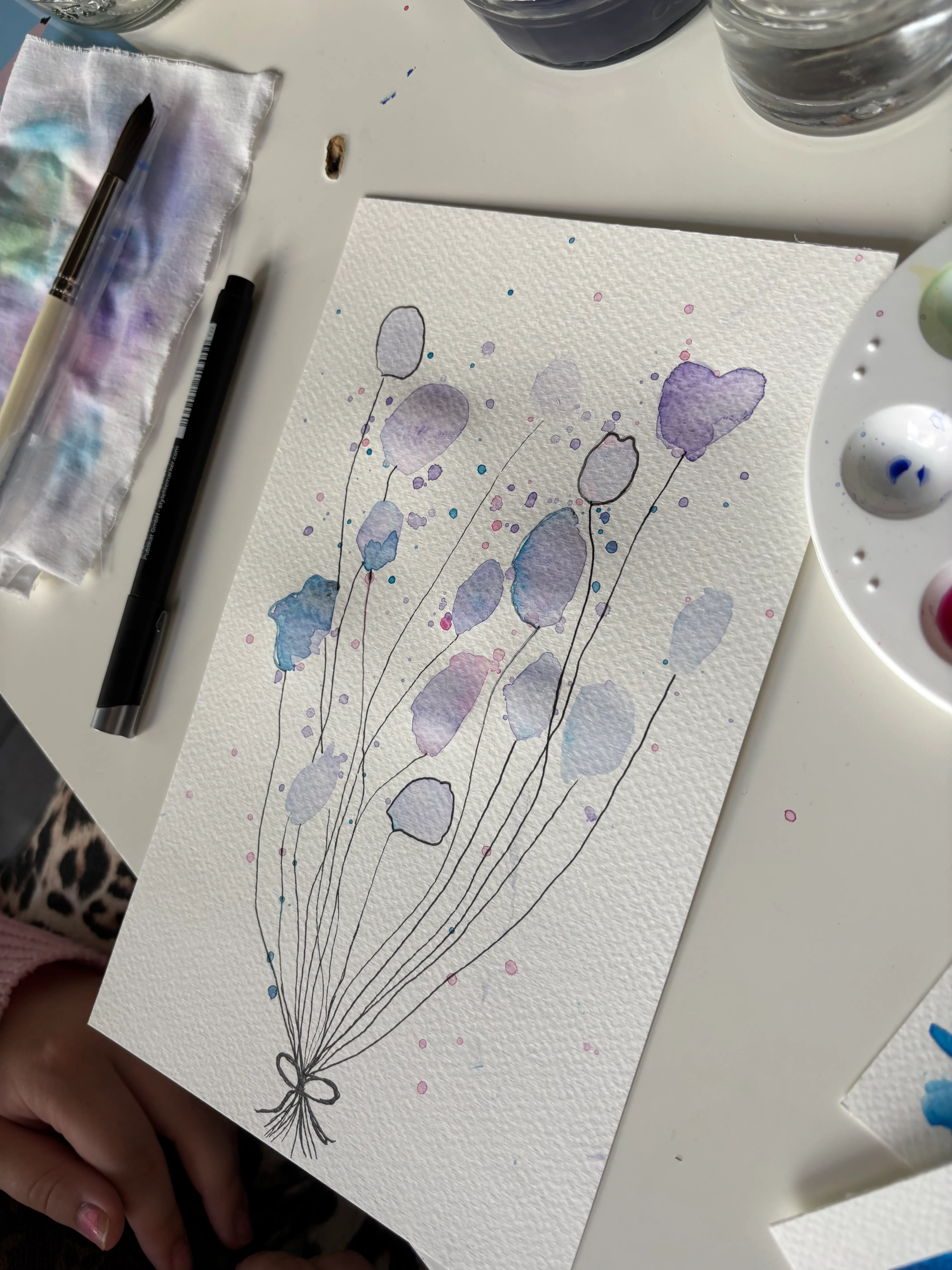 Watercolor balloon painting on art table.