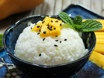 Sticky rice with mango cubes and mint in bowl.
