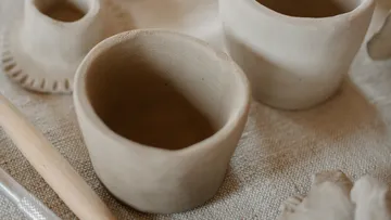 Unfertige Tonbecher auf einer strukturierten Oberfläche.