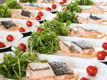 Fish dishes on plates with arugula and cherry tomatoes.