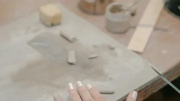 Hand formt Ton auf einem Arbeitstisch.