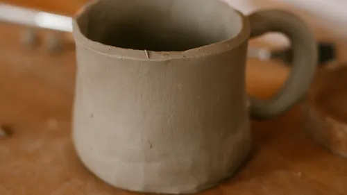 Unfinished clay mug on wooden table.