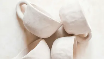 Four white ceramic cups on a table.