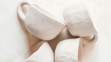 Vier weiße Keramikbecher auf einem Tisch.