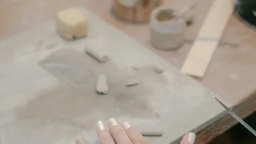 Hand sculpting clay on a workshop table.