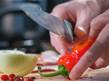 Schneide das Gemüse mit einem Messer in einer Küche.