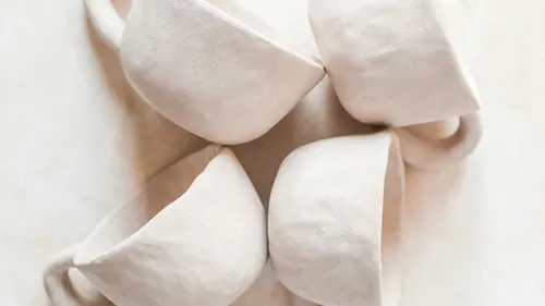 Four white ceramic cups with handles overlapping.