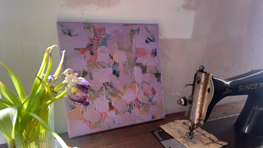 Vintage sewing machine beside purple abstract painting.