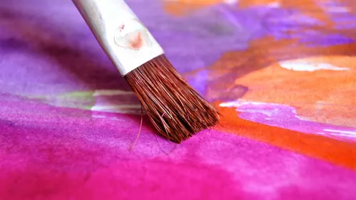 Pinsel trägt Farbe auf einer bunten Leinwand auf.