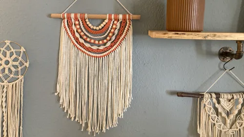 Handcrafted macramé wall hanging on blue wall.