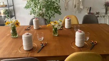 Tisch mit Garn, Blumen und Scheren für Basteln.