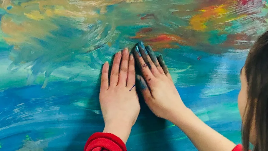 Hands painting on a colorful canvas.