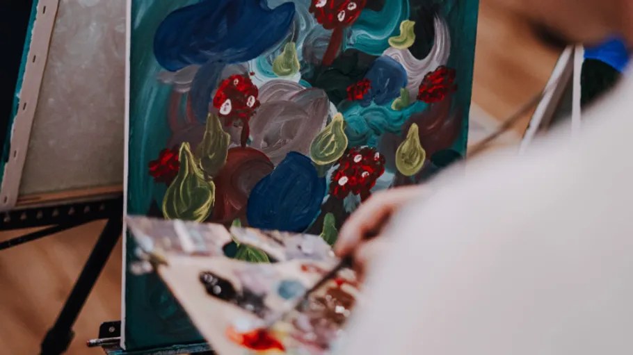 Artist painting colorful abstract artwork on canvas.