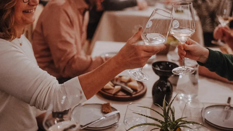 People clinking glasses around dining table.