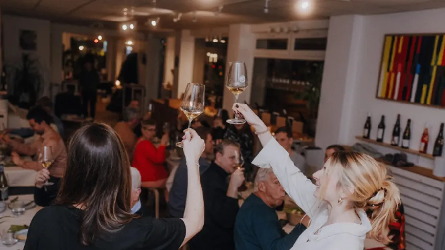 Zwei Frauen stoßen in einem vollen Restaurant an.