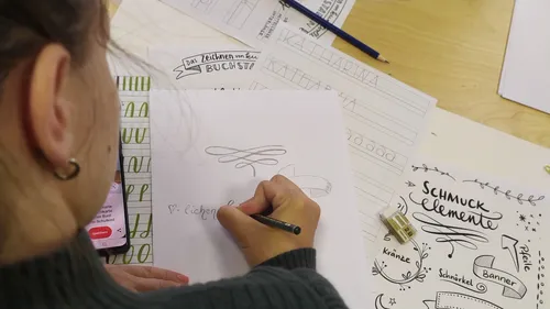 Person drawing decorative elements at a desk.
