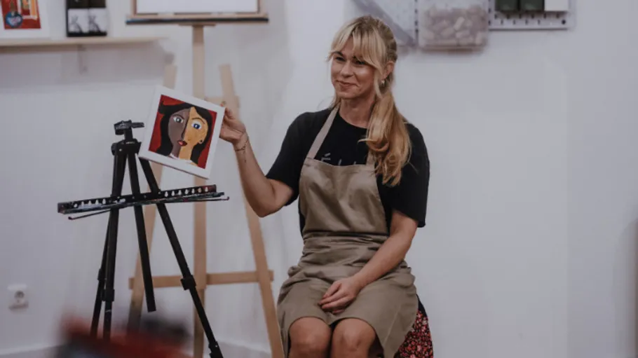 Frau hält Gemälde, sitzt im Kunststudio.