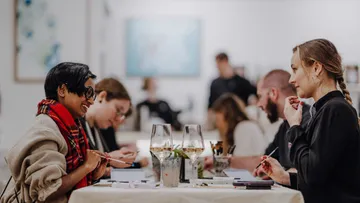 People drawing at tables in an art gallery.