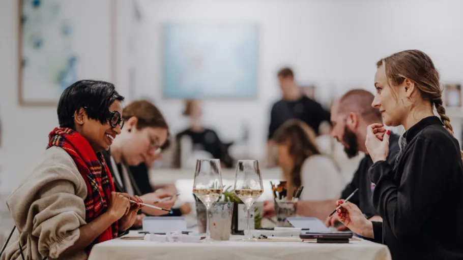 People drawing at tables in an art gallery.