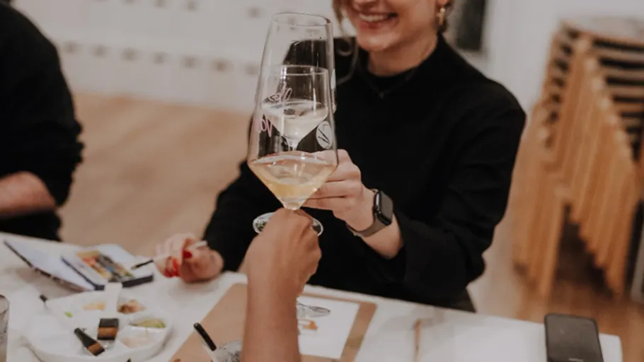 People clinking wine glasses at table.