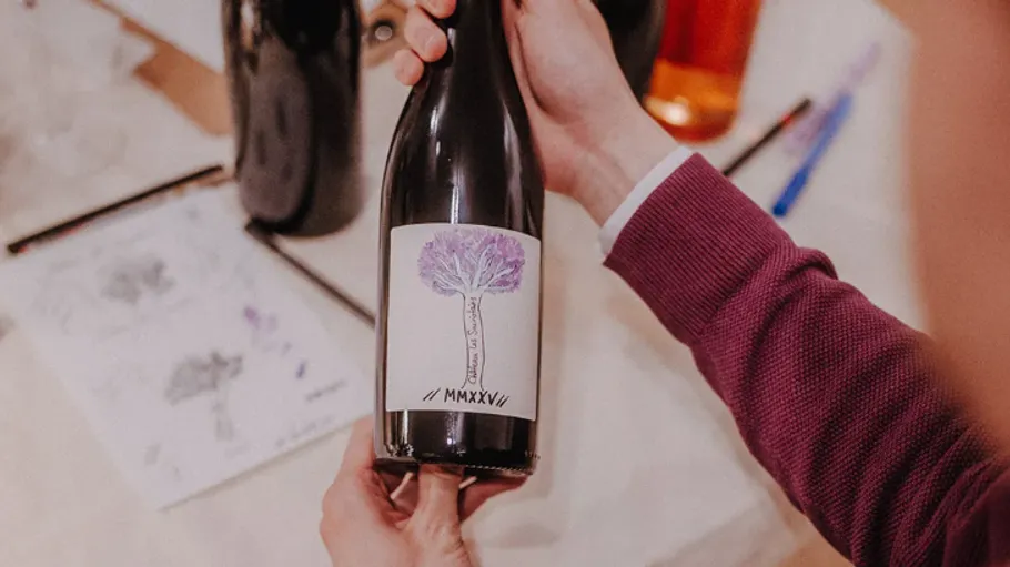 Person holding wine bottle with tree label.