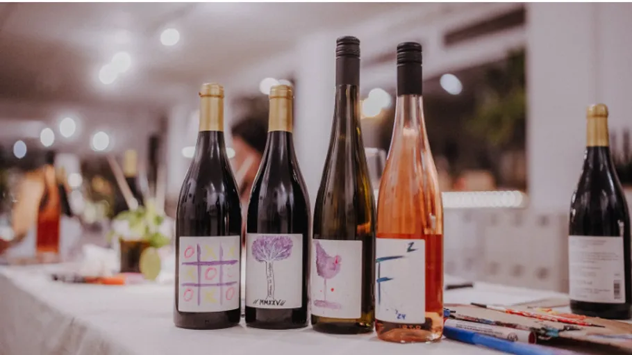 Four wine bottles with artistic labels on table.