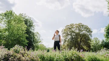 Person steht in einem Blumenfeld, wirkt nachdenklich.