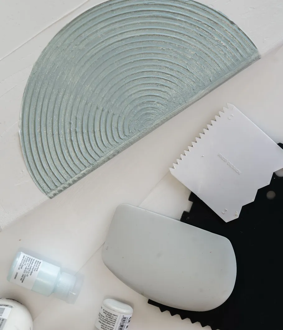 Textured semi-circle with tools and paint bottles.