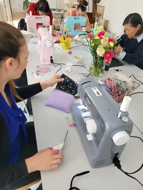 Women using sewing machines around a table.