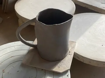 Clay mug drying on pottery wheel.