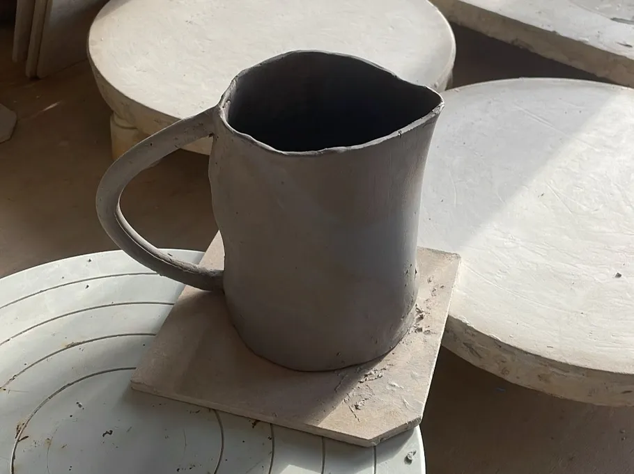 Clay mug drying on pottery wheel.
