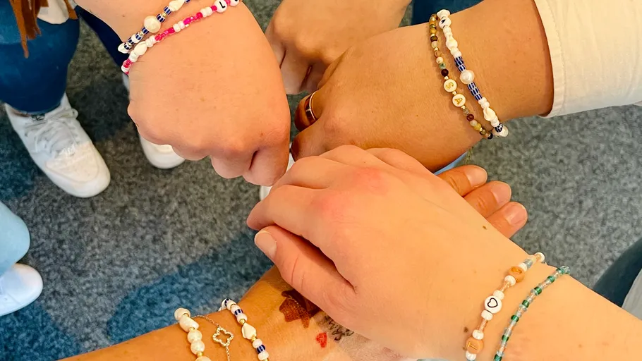 Vier Hände mit Perlenarmbändern, Nahaufnahme.