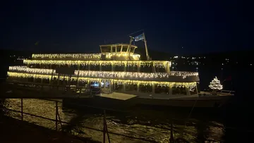 Boot mit Lichtern auf dunklem Wasser.