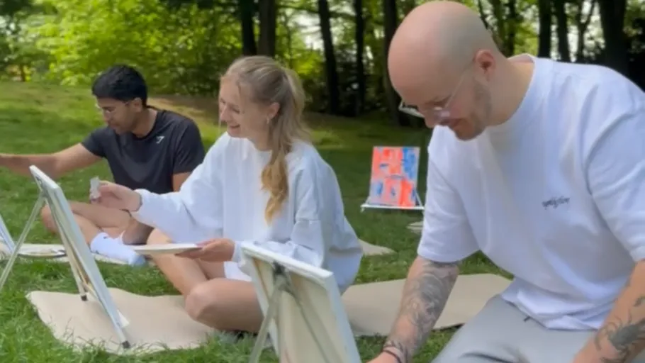 Three people painting outdoors in a park.