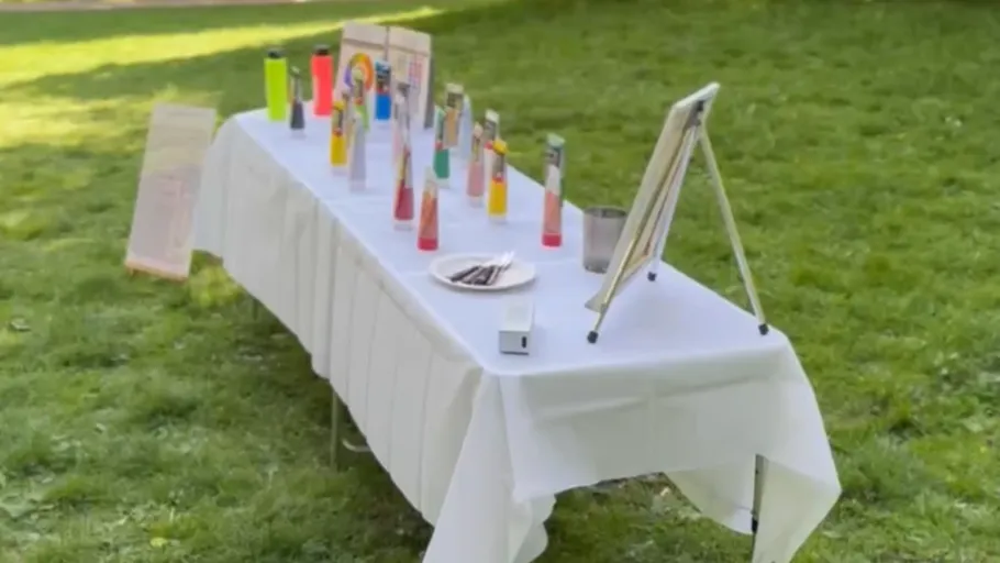Table with drinks on a grassy field.