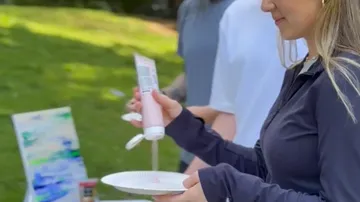 Person squeezing paint onto a plate outdoors.