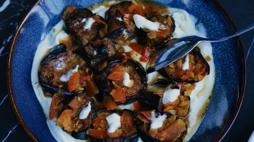 Eggplant dish with yogurt and tomato garnish.