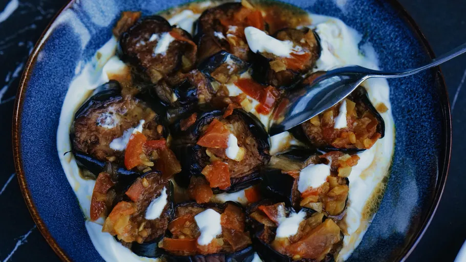 Eggplant dish with yogurt and tomato garnish.